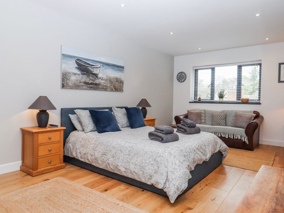 A bedroom with a bed, nightstand, sofa, and window at Lower Moorwood in Moorwood near Bovey Tracey