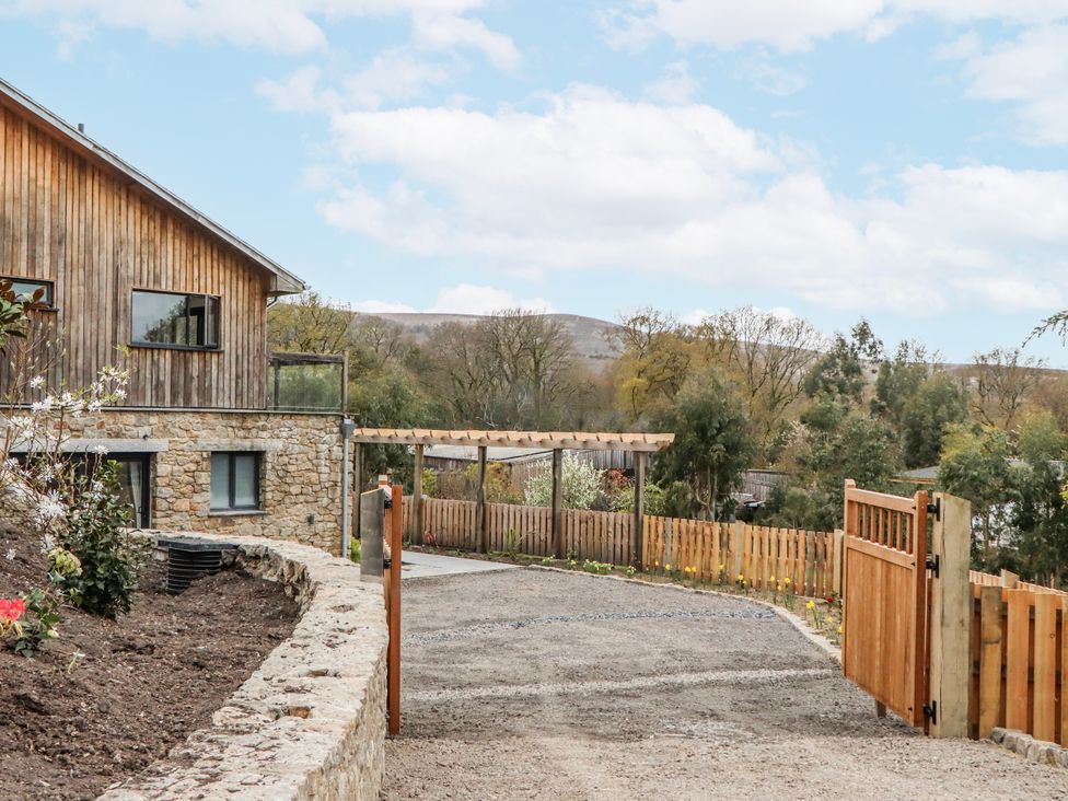 An exterior view of a house with a gravel driveway and wooden fence at Lower Moorwood Moorwood near Bovey Tracey