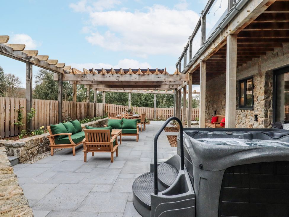 An outdoor patio area with a hot tub and seating at Lower Moorwood in Moorwood near Bovey Tracey