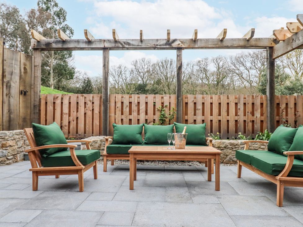 An outdoor patio with green seating and a coffee table at Lower Moorwood in Moorwood near Bovey Tracey
