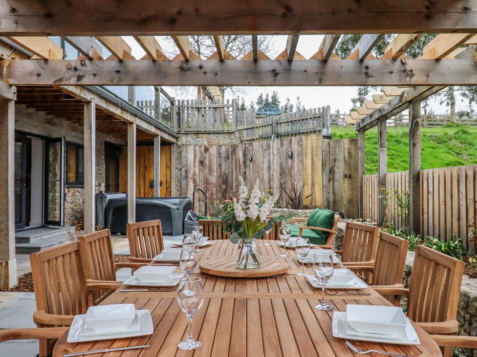 An outdoor dining area with a wooden table and chairs at Lower Moorwood in Moorwood near Bovey Tracey