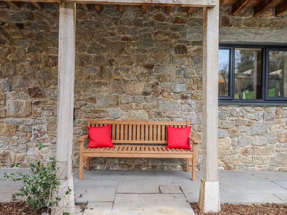 An outdoor seating area with a wooden bench at Lower Moorwood in Moorwood near Bovey Tracey
