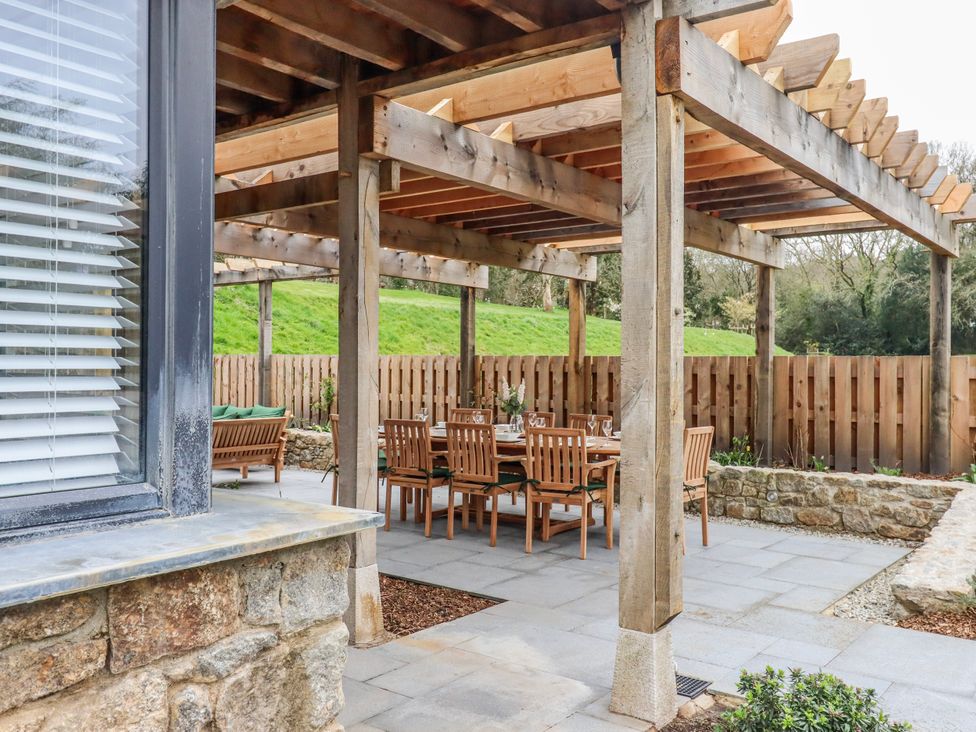 An outdoor patio with a dining table and wooden chairs at Lower Moorwood in Moorwood near Bovey Tracey