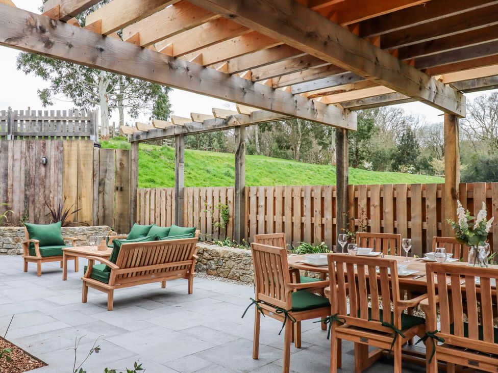 An outdoor dining area with a wooden table and chairs at Lower Moorwood in Moorwood near Bovey Tracey