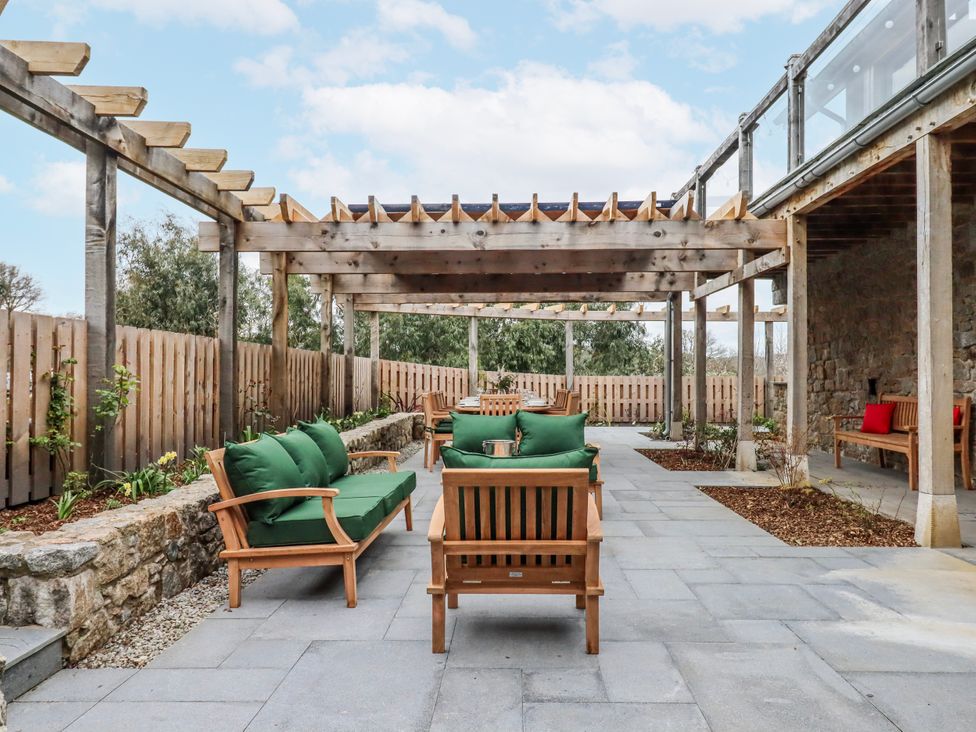 An outdoor patio with seating under a pergola at Lower Moorwood in Moorwood near Bovey Tracey