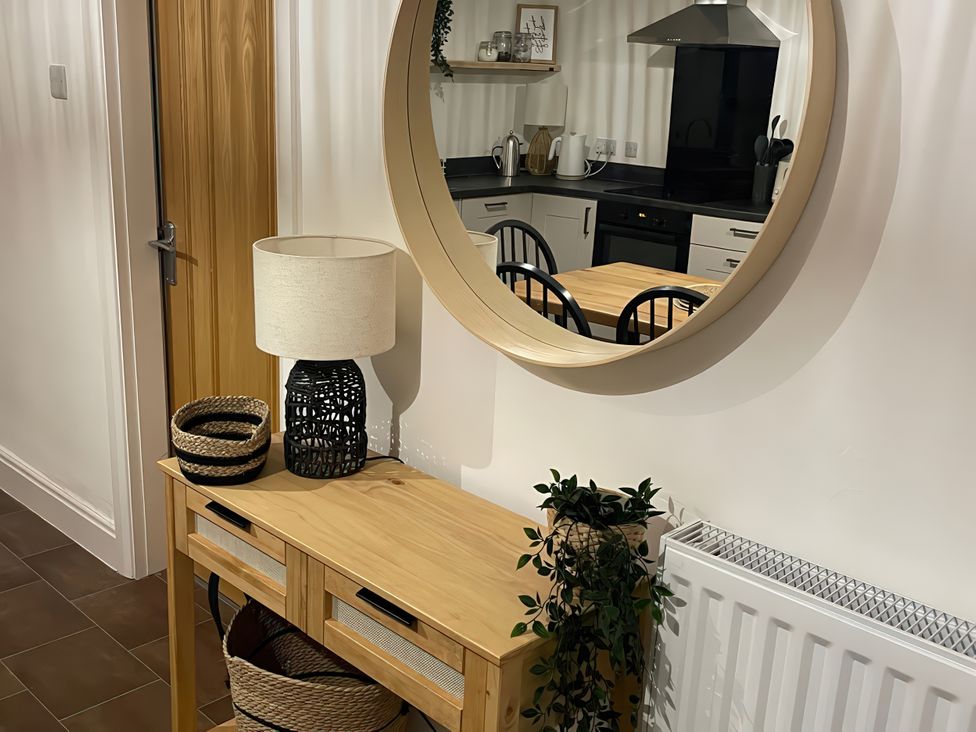 A console table with a lamp and baskets in a hallway at Plas Darien Apartment 7 Trearddur Bay