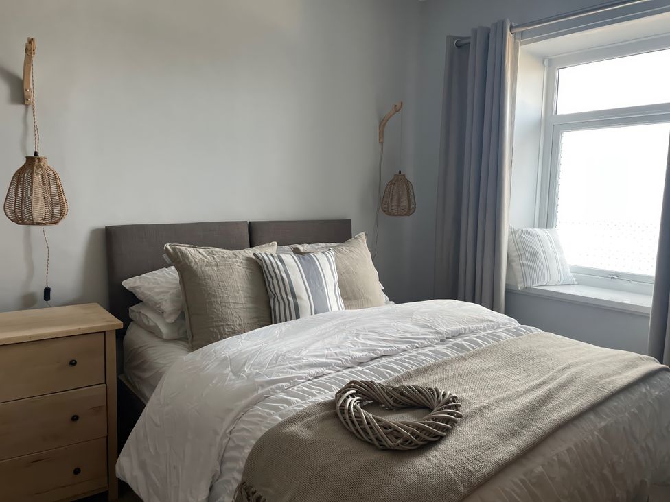A bedroom with a bed and nightstand at Plas Darien Apartment 7 Trearddur Bay