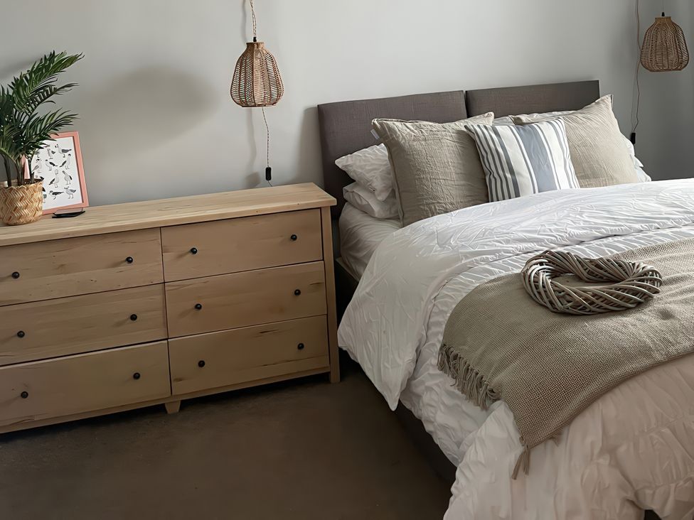A bedroom with a bed and dresser in Plas Darien Apartment 7 in Trearddur Bay