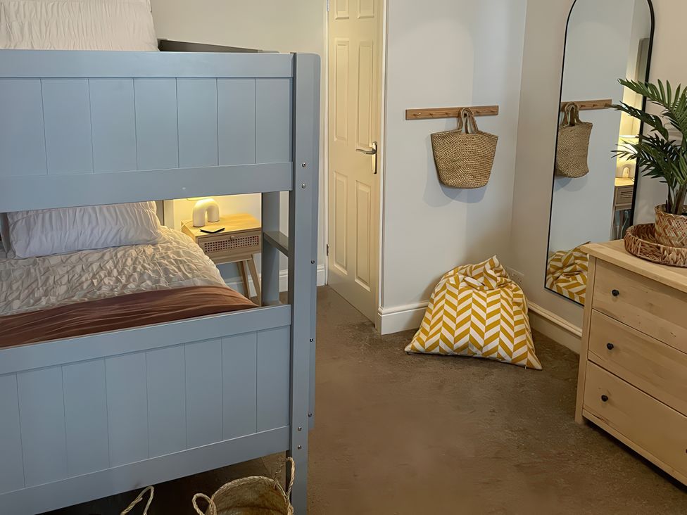 A bedroom with a bunk bed and mirror at Plas Darien Apartment 7 Trearddur Bay