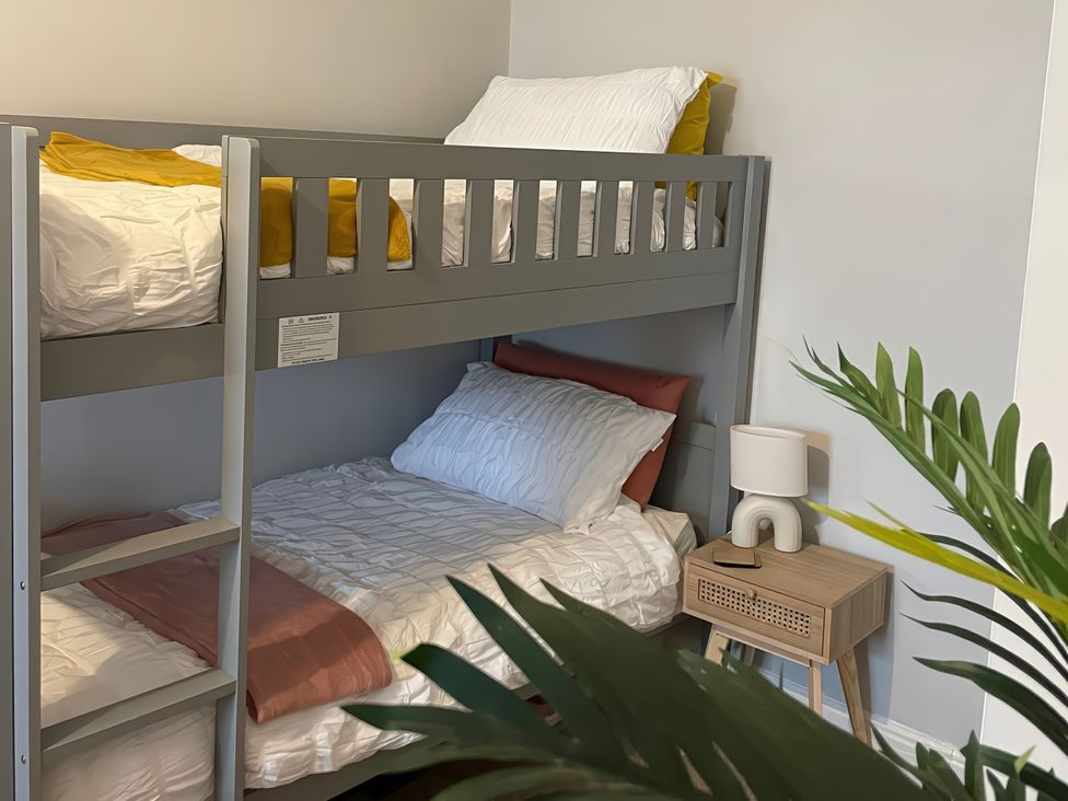 A bunk bed with a nightstand and lamp in a bedroom at Plas Darien Apartment 7 Trearddur Bay