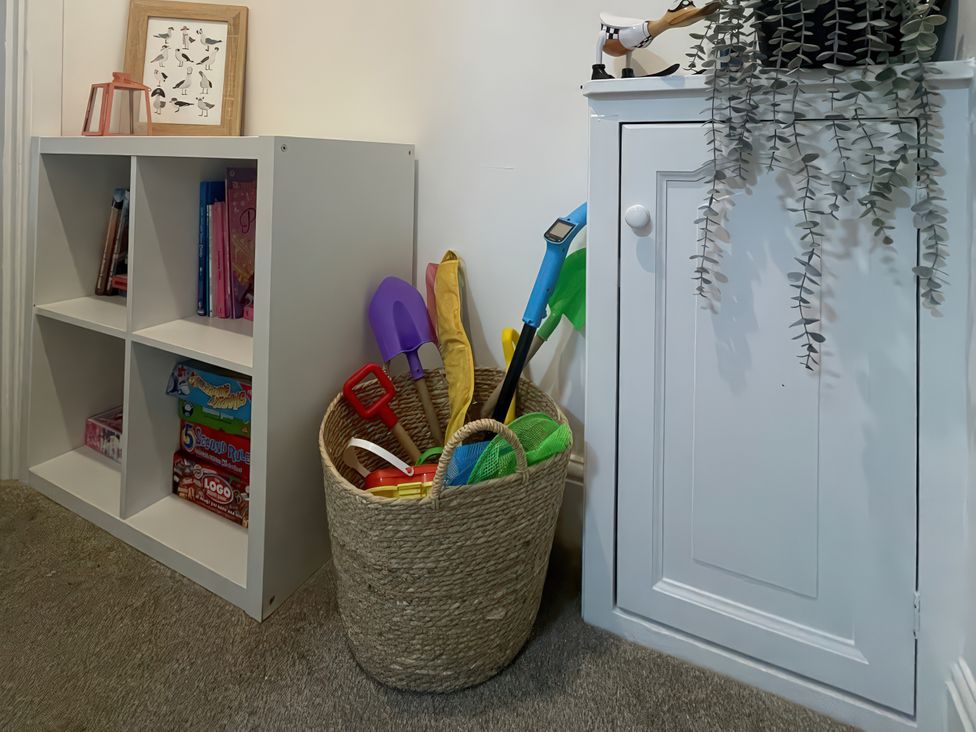 A playroom with a bookshelf and a storage basket of toys at Plas Darien Apartment 7 in Trearddur Bay