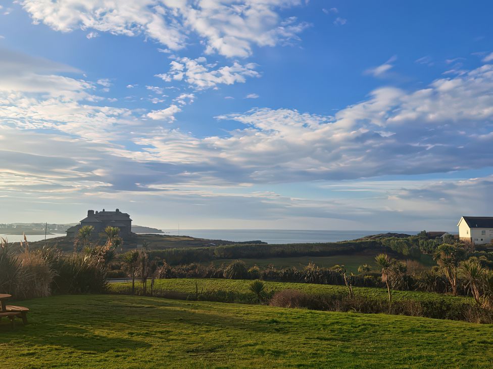 A view of the sea and a building from a grassy area at Plas Darien Apartment 7 in Trearddur Bay