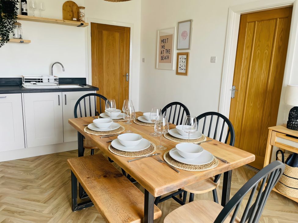 A dining room with a wooden table set for a meal at Plas Darien Apartment 7 Trearddur Bay