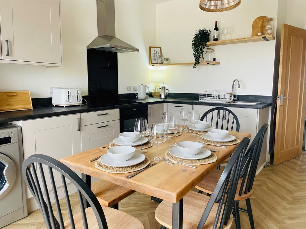 A kitchen with dining table set for dinner at Plas Darien Apartment 7 in Trearddur Bay