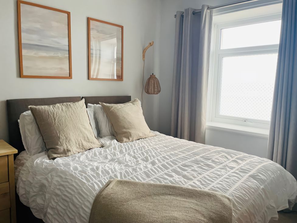 A bedroom with a bed and wall art at Plas Darien Apartment 7 Trearddur Bay