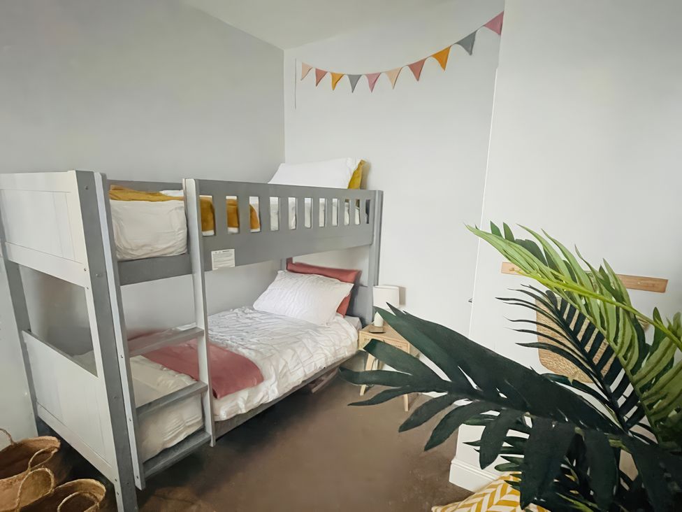 A bedroom with a bunk bed and decorative items at Plas Darien Apartment 7 Trearddur Bay