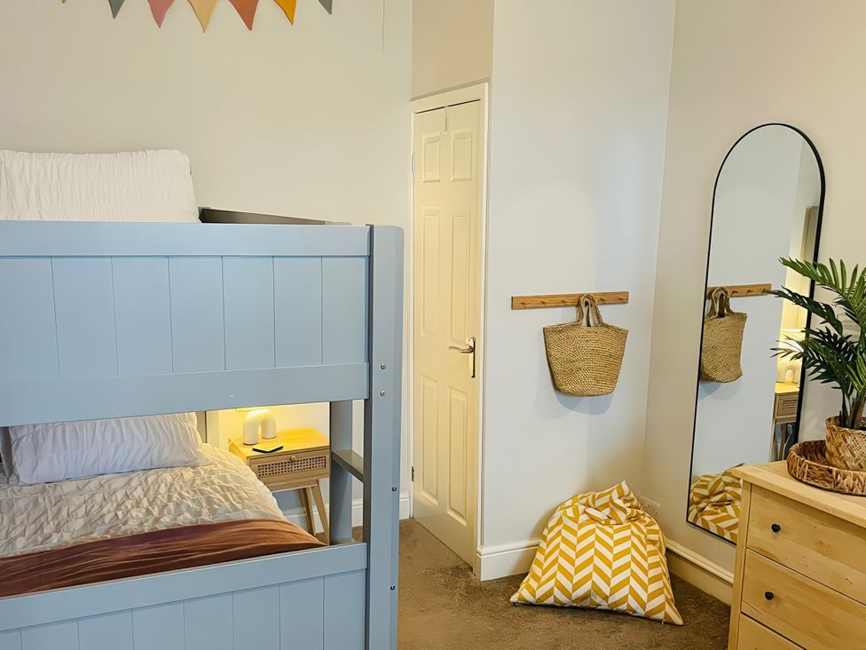 A bedroom with a bunk bed and storage unit at Plas Darien Apartment 7 Trearddur Bay