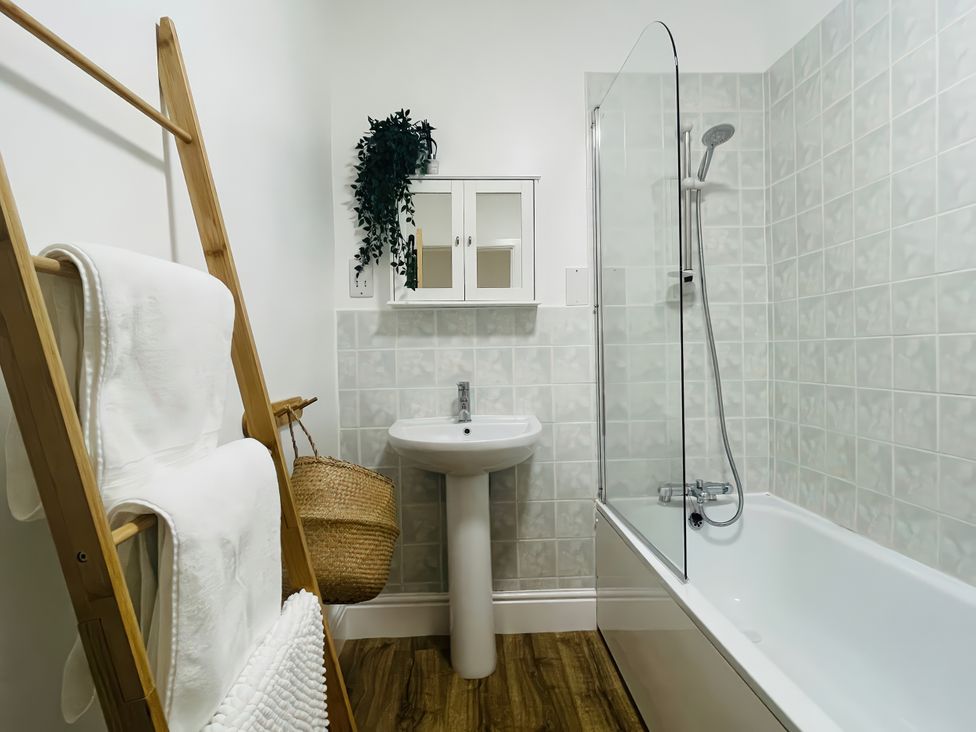 A bathroom with a bathtub, sink, and towel ladder at Plas Darien Apartment 7 Trearddur Bay