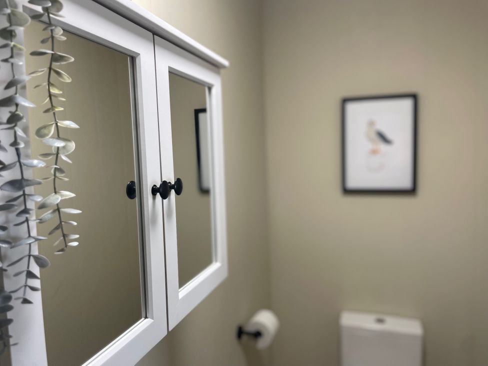 A bathroom with a mirror cabinet and framed artwork at No.7 Plas Darien Trearddur Bay