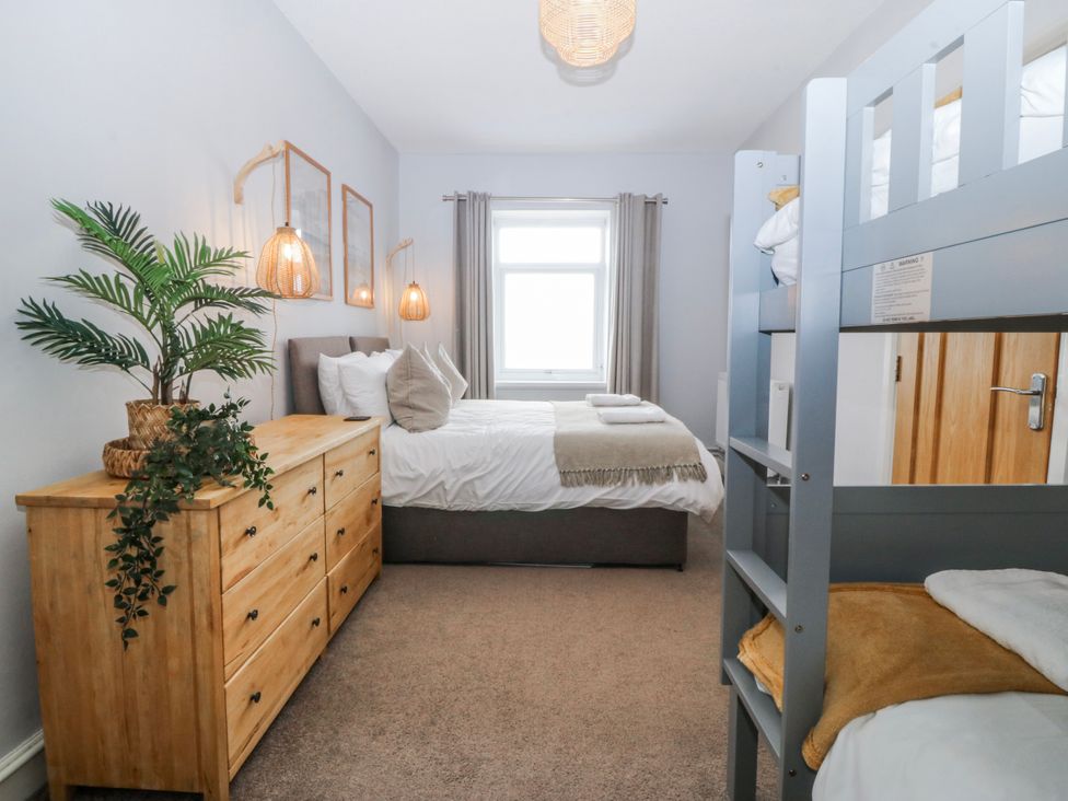 A bedroom with a double bed and bunk bed at No.7 Plas Darien in Trearddur Bay