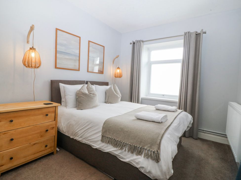 A bedroom with a bed and dresser at No.7 Plas Darien in Trearddur Bay