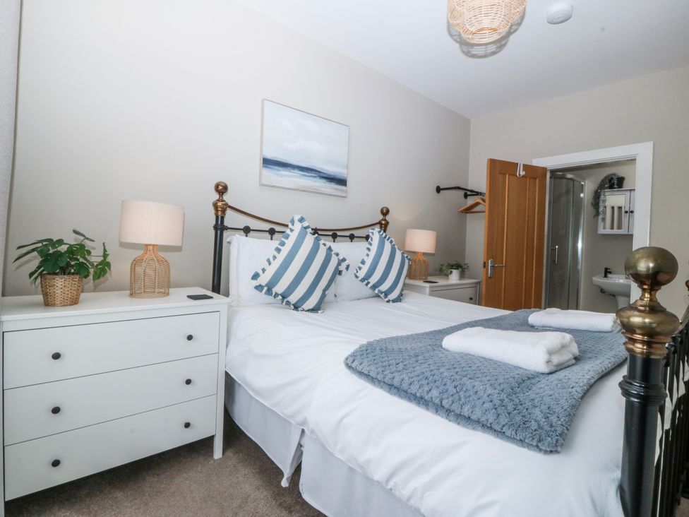 A bedroom with a bed and bedside lamp at No.7 Plas Darien, Trearddur Bay