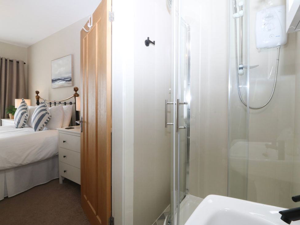 A bedroom with a bed and shower at No.7 Plas Darien in Trearddur Bay