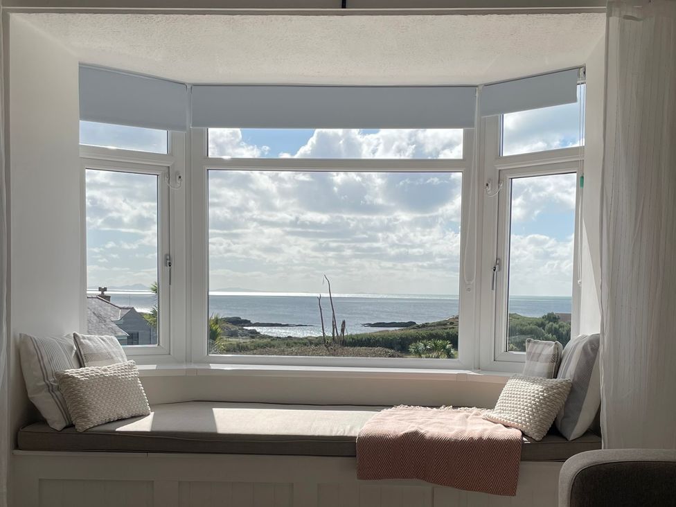 A window seat with cushions and a throw blanket at No.7 Plas Darien Trearddur Bay