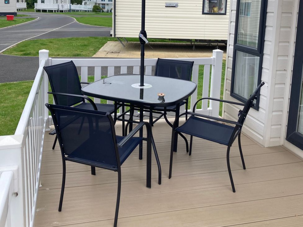 A table and chairs on a deck at 128 Crosswinds in Bembridge