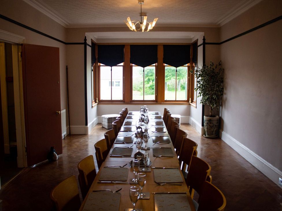 A dining room with a long table and chairs at Crannoch Self Catering in Buckie