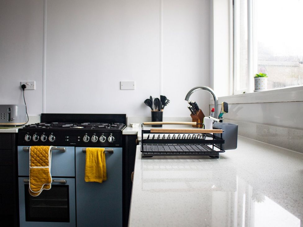 A kitchen with a sink, cooker, and dish rack at Crannoch Self Catering in Buckie
