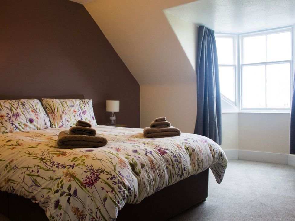 A bedroom with a bed, lamp, and window at Crannoch Self Catering in Buckie