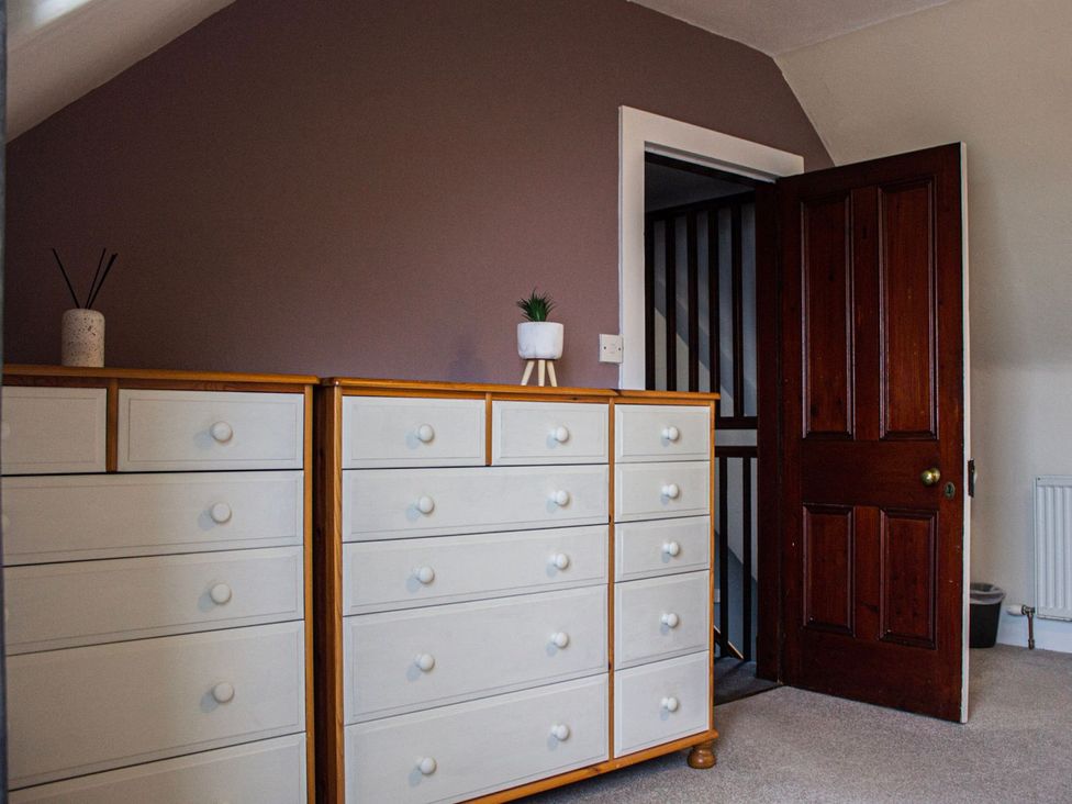 A bedroom with a dresser and door at Crannoch Self Catering, Buckie