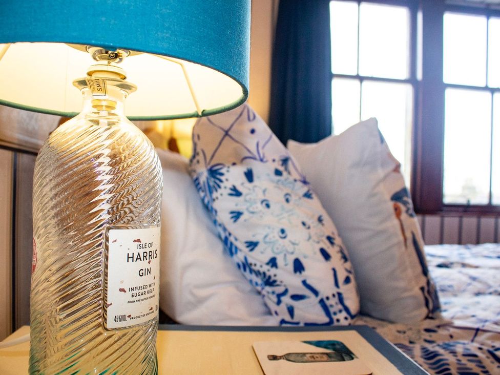 A lamp and a bottle on a table in a bedroom at Crannoch Self Catering in Buckie