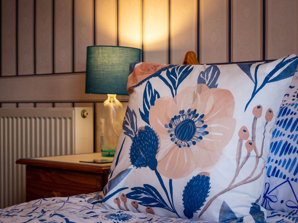 A bedroom with a floral pillow and lamp at Crannoch Self Catering in Buckie