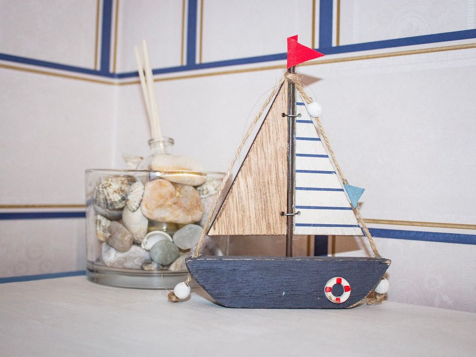 A decorative wooden boat next to a glass container with pebbles at Crannoch Self Catering in Buckie