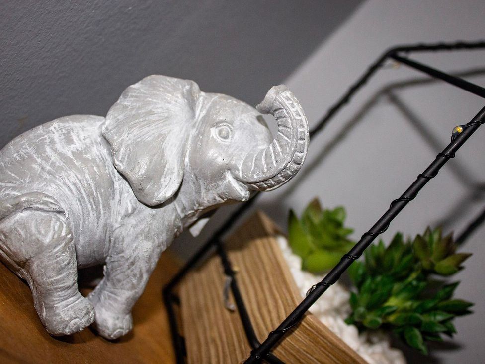 A decorative elephant statue next to a plant in a wooden box