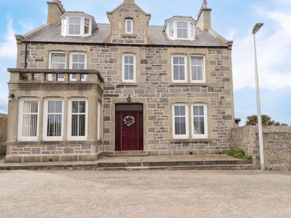 A stone building with windows and a red door at Crannoch Self Catering Cullen