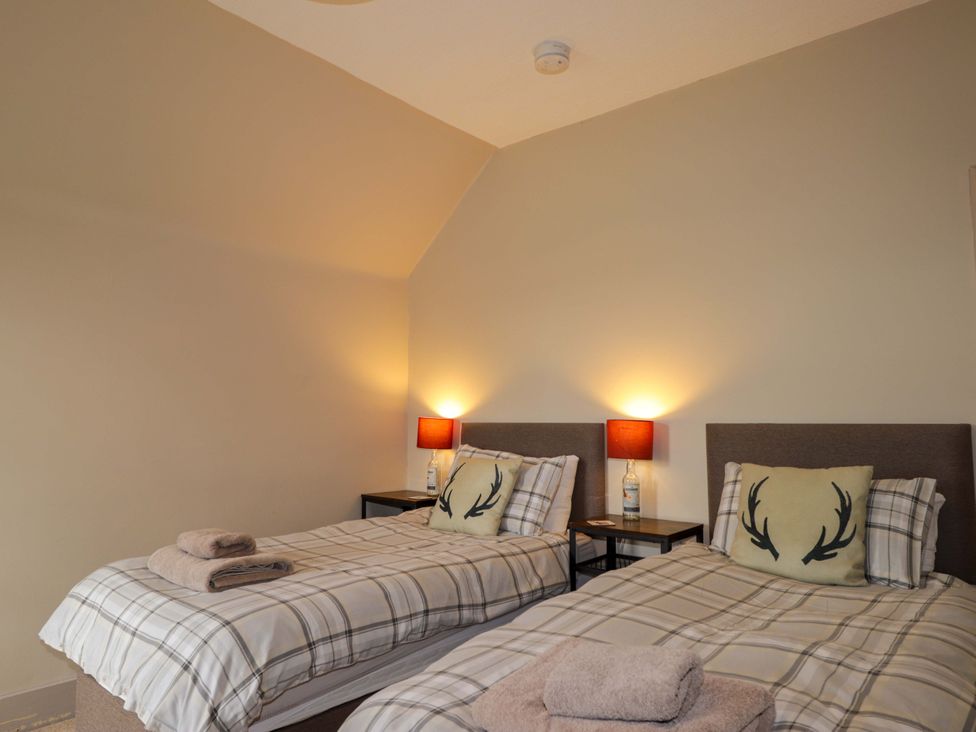 A bedroom with two beds and lamps at Crannoch Self Catering in Cullen