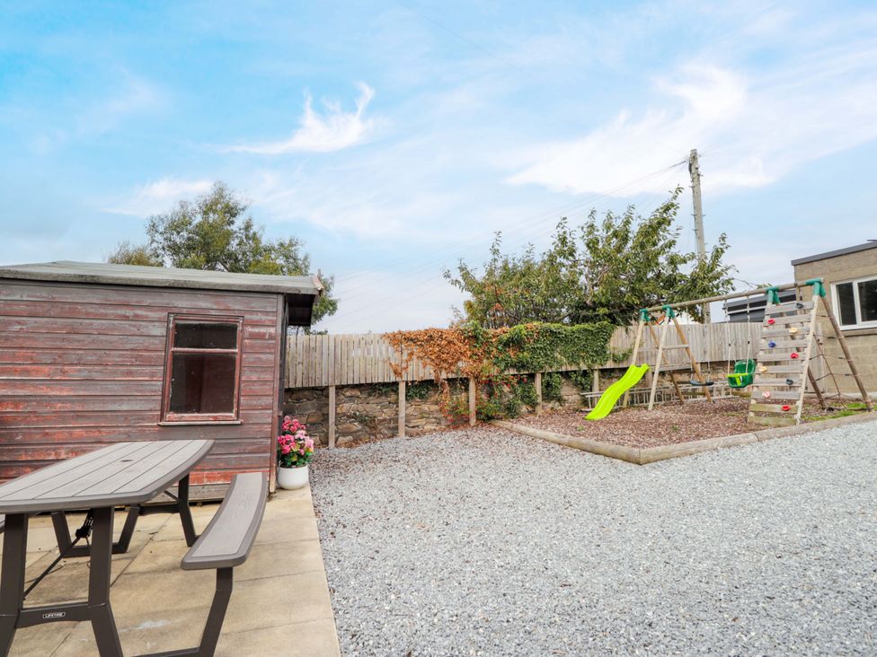 A garden with a shed, table, swing set, and slide at Crannoch Self Catering in Cullen