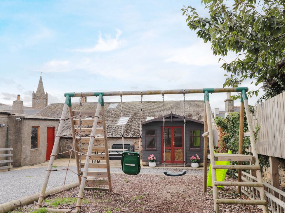 A garden with a swing set and playhouse at Crannoch Self Catering in Cullen