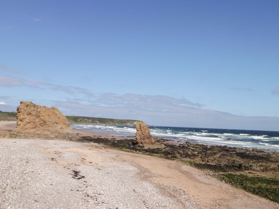 A beach with rocks and waves at Crannoch Self Catering in Cullen