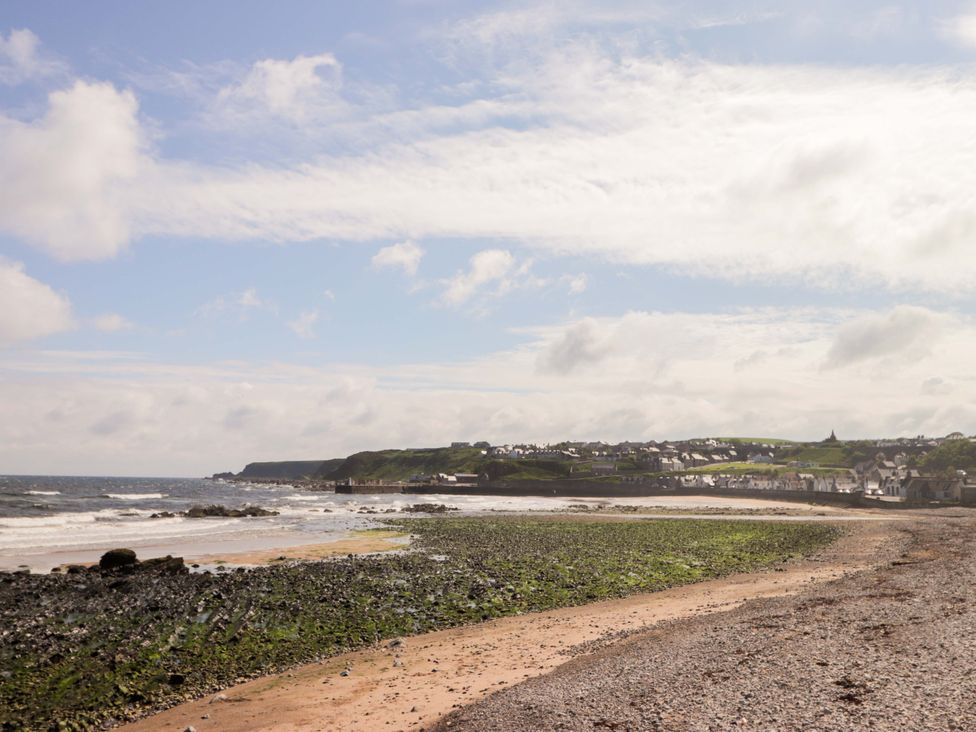 A beach with rocks and buildings along the shoreline at Crannoch Self Catering in Cullen