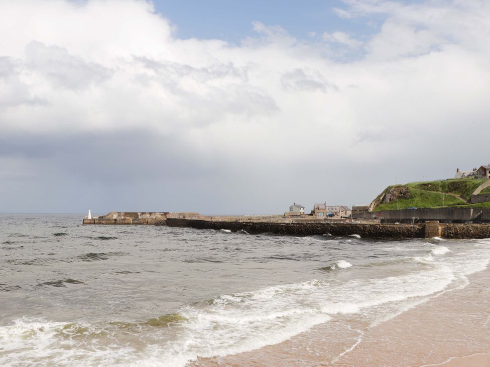 A coastal scene with a pier and lighthouse at Crannoch Self Catering in Cullen