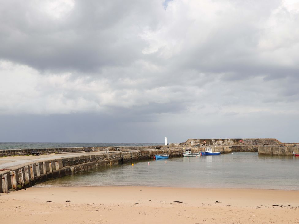 A beach with boats and a pier at Crannoch Self Catering Cullen