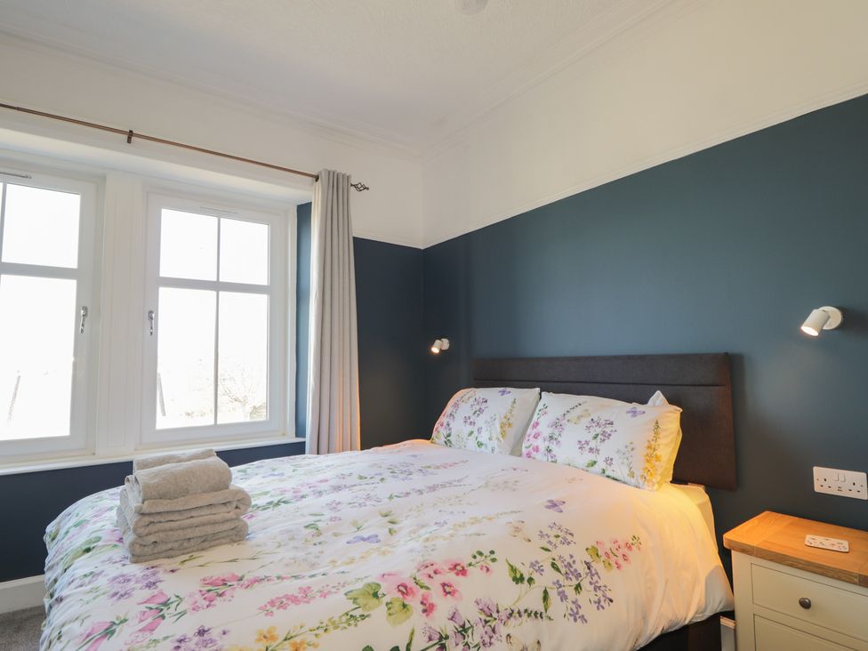 A bedroom with a bed and windows at Crannoch Self Catering in Cullen
