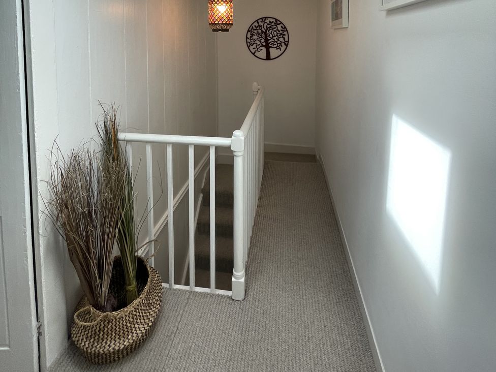 A hallway with a stair railing and plants in a basket at 51 North Street in Wareham