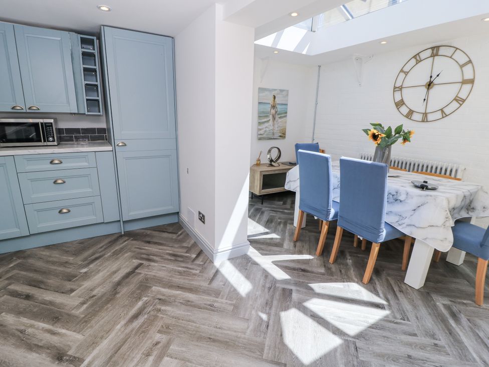 A kitchen and dining area with blue cabinets and a dining table at Delightful Dorset House By Wareham River in Wareham
