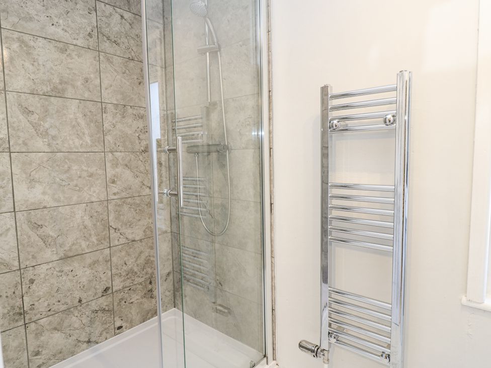 A shower with glass door and towel rail at Delightful Dorset House By Wareham River, Wareham