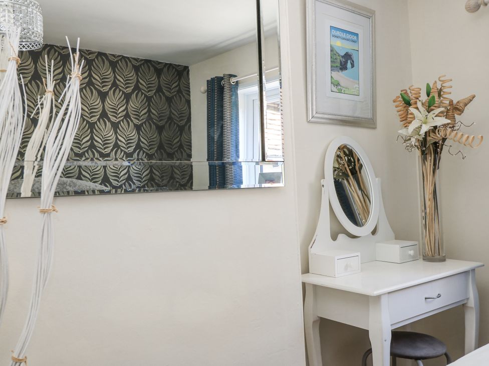 A dressing table with a mirror and vase at Delightful Dorset House By Wareham River in Wareham